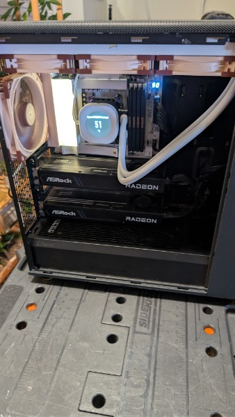 Open AMD workstation with two ASRock Radeon graphics cards and a white liquid CPU cooler.